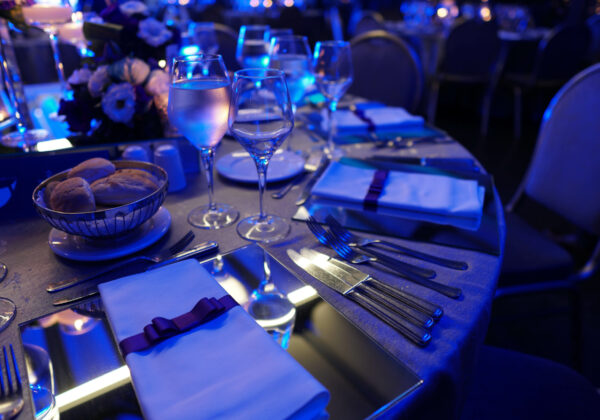 Formal fundraiser gala table setting with blue event lighting — nonprofit gala catering Bay Area