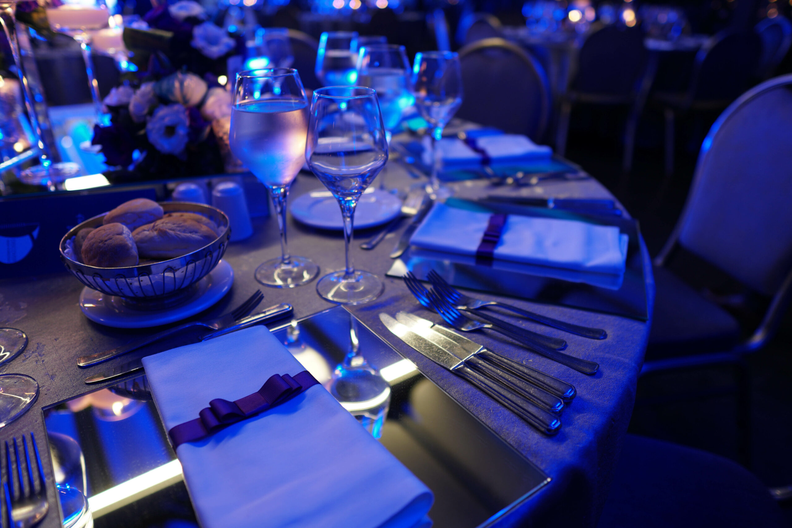 Formal fundraiser gala table setting with blue event lighting — nonprofit gala catering Bay Area